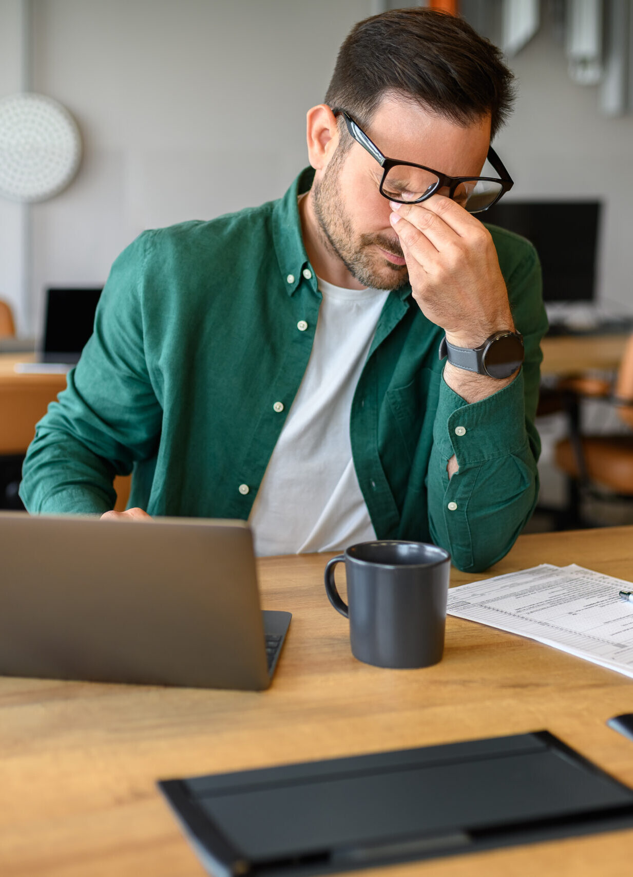 Exhausted male manager rubbing eyes in stress while working over project on laptop at his workplace Exhausted male manager rubbing eyes in stress while working over project on laptop at his workplace